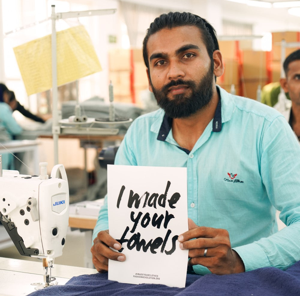 Factory worker holding an "I made your towels" poster